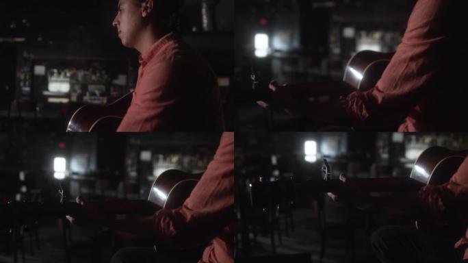 一位拉丁裔音乐家在一个昏暗的空酒吧里演奏木吉他
