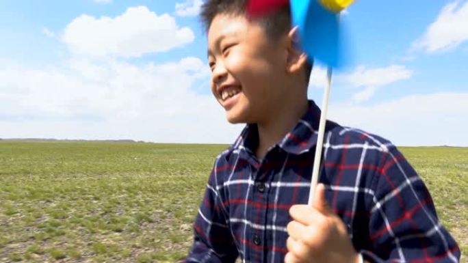在草原上与风车一起奔跑的亚洲男孩