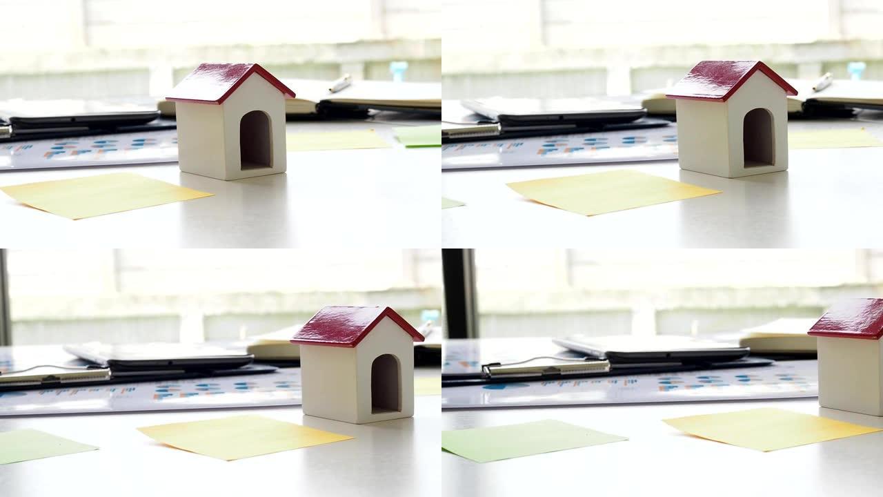 建筑师办公桌上的红色屋顶房屋模型。平移左枪。