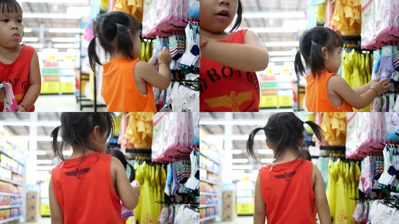 可爱的亚洲小女孩和她的妹妹在购物中心购物很开心。