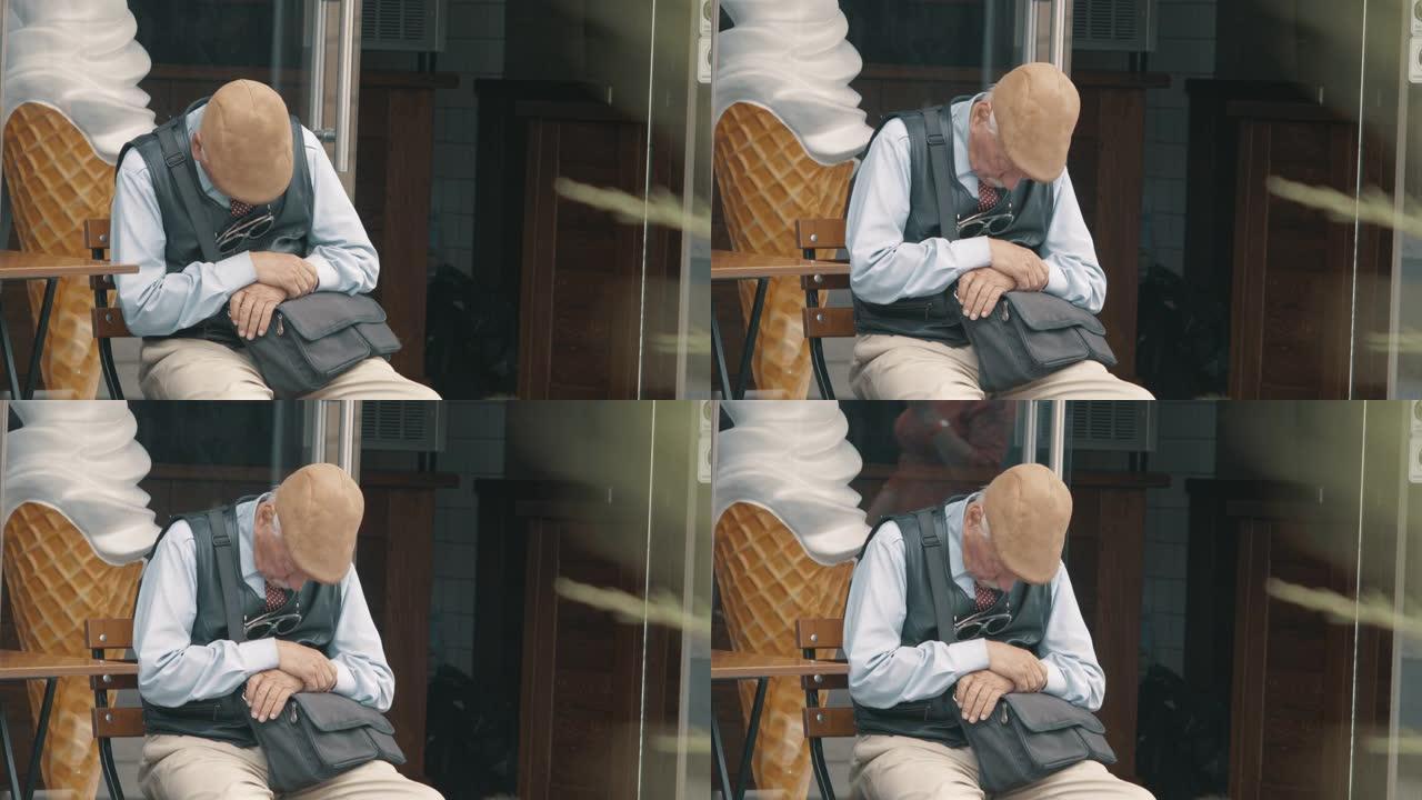 戴着灰色胡须和头发的帽子的老人坐在街上的椅子上睡着了。人们走过一个熟睡的老人。4k. 4k视频。60