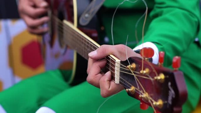 穿着绿色西装的男人在演奏黑色原声吉他。