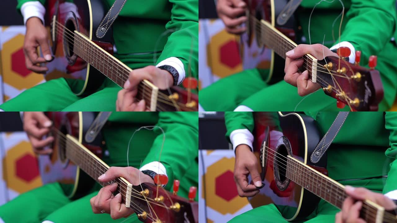 穿着绿色西装的男人在演奏黑色原声吉他。