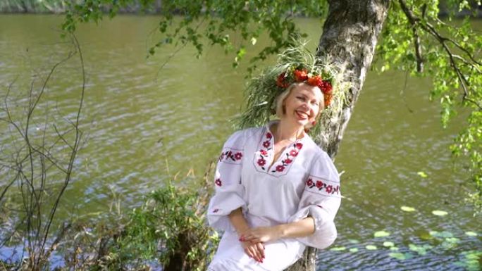 穿着斯拉夫传统服装的漂亮女人躺在桦树的树干上