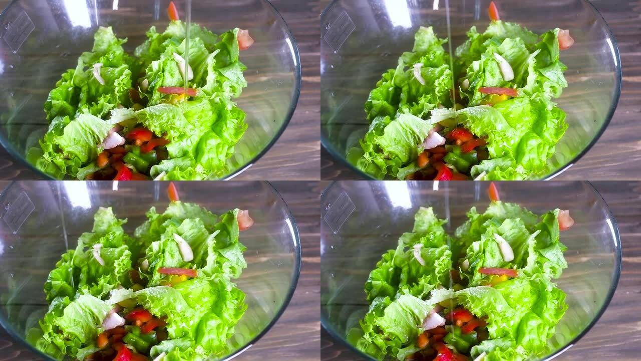 厨师用橄榄油浇灌沙拉。一股稀薄的油流倒在一个大玻璃杯里的新鲜天然蔬菜沙拉上。健康的饮食食品。慢动作。