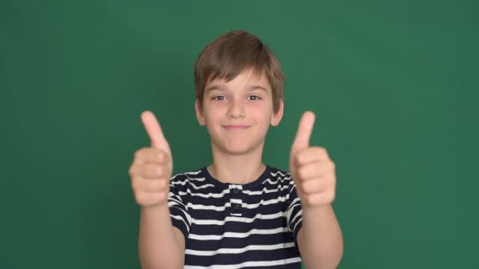 绿色屏幕上竖起大拇指的小男孩
