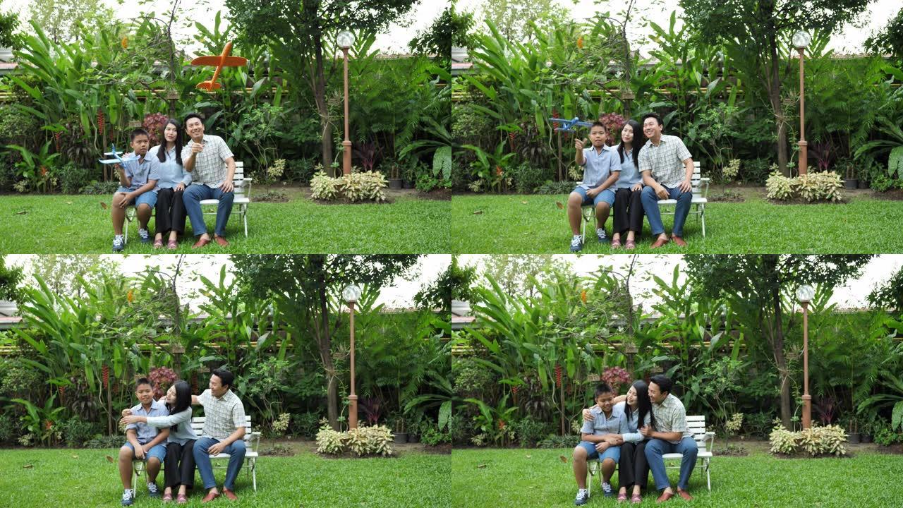 快乐的亚洲家庭母亲，父亲和儿子。他们在家里的花园里一起玩飞机模拟。家庭度假。慢动作
