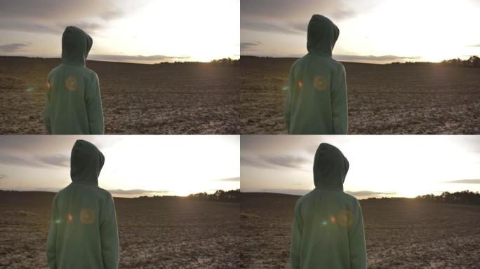 男孩在日落时沿着田野散步