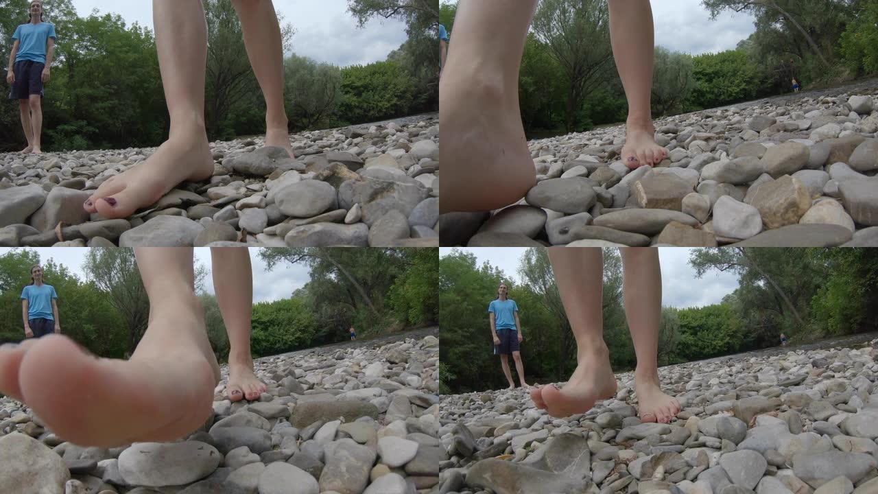 成年妇女在河岸的鹅卵石上赤脚行走的特写镜头