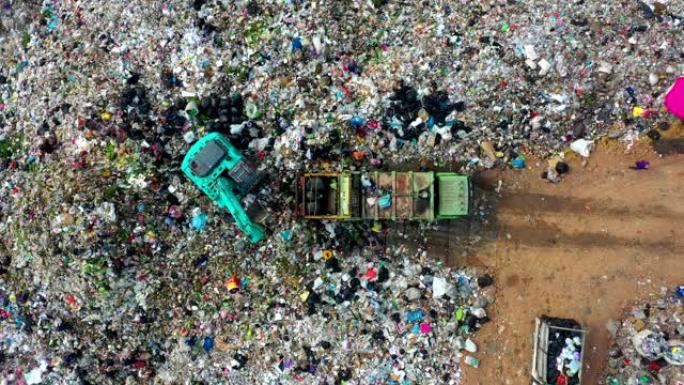垃圾堆在垃圾场或露天垃圾填埋场，垃圾车倾倒污染垃圾场的废物，地表和地下水污染，现代液压。空中俯视图