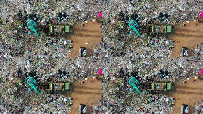 垃圾堆在垃圾场或露天垃圾填埋场，垃圾车倾倒污染垃圾场的废物，地表和地下水污染，现代液压。空中俯视图
