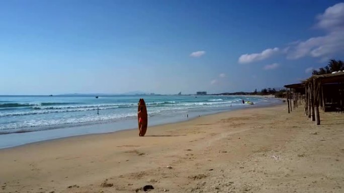 女人在海滩上的冲浪板上对着蓝天下的波浪冲浪