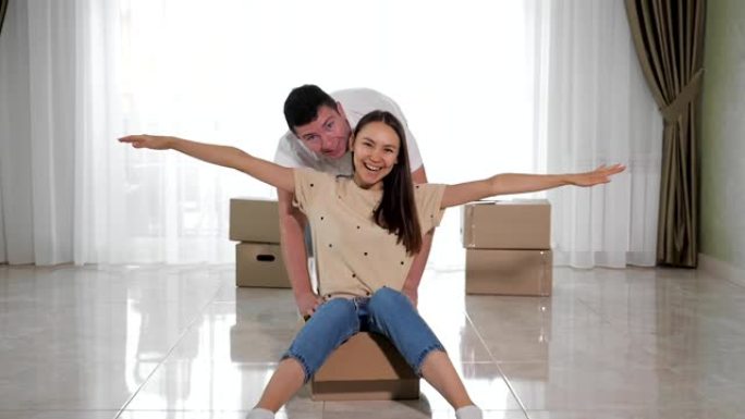 丈夫在白色地板上的大盒子里骑着微笑的妻子