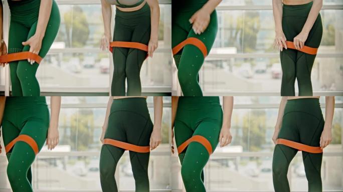 两名穿着绿色腿的妇女在健身室训练-在大腿之间放一条伸缩带