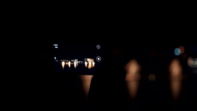 在智能手机上观看，拍照和拍摄视频的人的剪影带有鲜艳的喷泉。