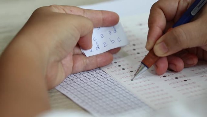 手拿铅笔做数学选择题考试和考试作弊，手拿答案纸。学生使用公式数学表在考试中作弊。