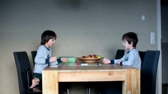 两个孩子，男孩兄弟，在厨房里在家玩桌上游戏