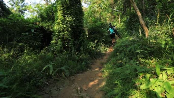 女自行车手在热带森林步道的斜坡上骑山地车