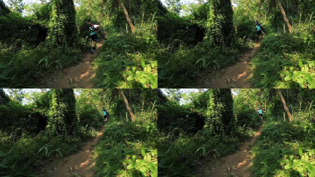 女自行车手在热带森林步道的斜坡上骑山地车