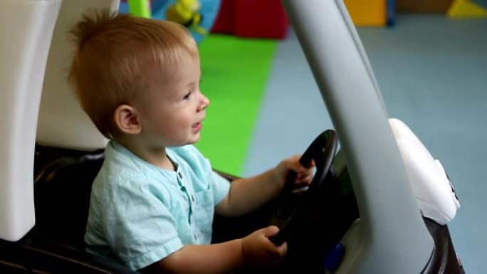 慢动作。儿童驾驶玩具车的轮子。儿童游戏中心。男孩开玩具车。