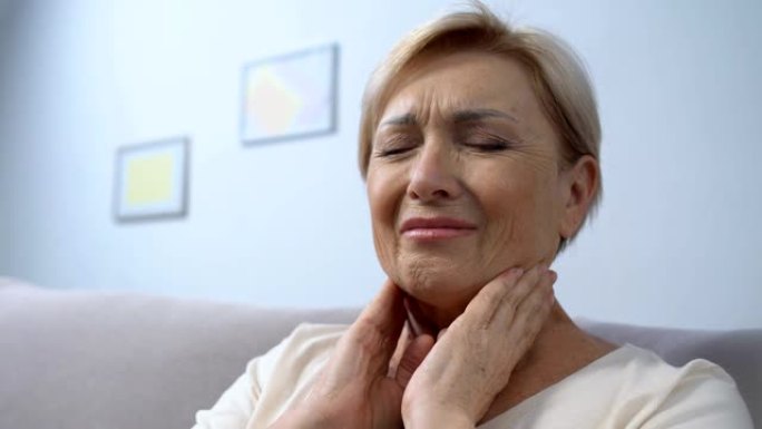老年妇女触摸喉咙疼痛，心绞痛问题，季节性疾病