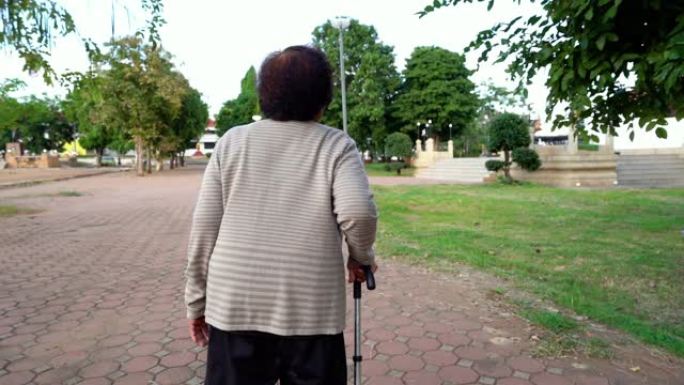 在公园里用拐杖走路的老年妇女的慢动作