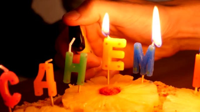 慢动作特写镜头人们在蛋糕上点燃庆祝蜡烛