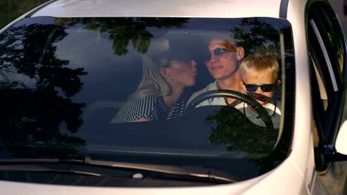 旅行中一个戴着墨镜的年轻家庭的肖像，车上有一个孩子。