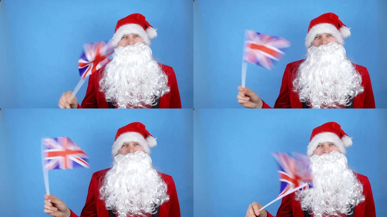 一个穿着圣诞老人服装留着胡子的男人在蓝色背景上挥舞着大不列颠的旗帜。世界各地的新年假期概念