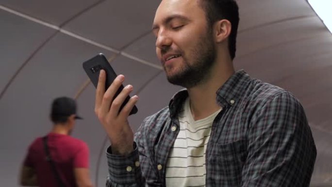 随性微笑的男人在地铁的自动扶梯上完成了电话交谈
