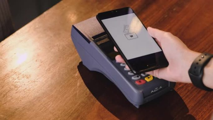 慢动作特写手使用移动电子钱包应用程序在咖啡馆柜台酒吧的信用卡机上支付非接触式。无线支付nfc生活方式
