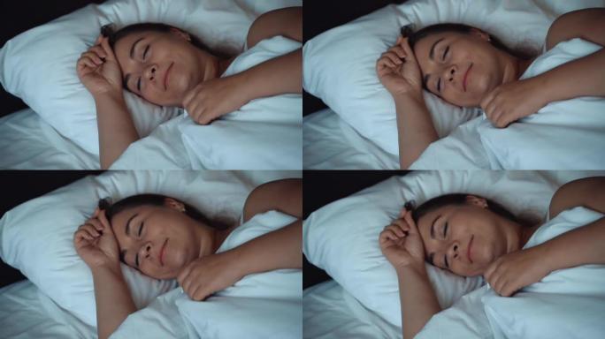 平静的年轻漂亮女人在舒适的大床里睡觉和微笑，慢动作