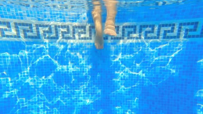 在游泳池中冷却的脚的淹没视图