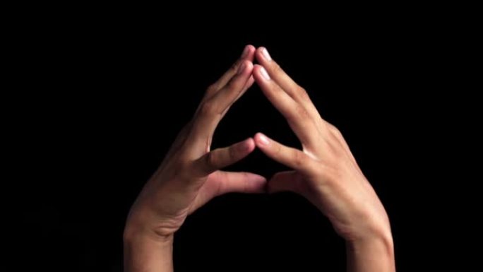 一对人类的手站起来，展示了在黑色背景上孤立的哈基尼瑜伽手印手势。