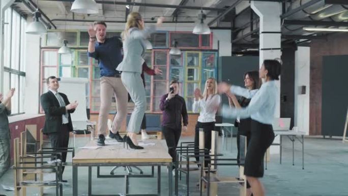 同事们在桌子上跳舞，用扩音器唱歌，到处乱扔钱。员工庆祝成功。企业党业务团队。现代时尚的办公室内部。办