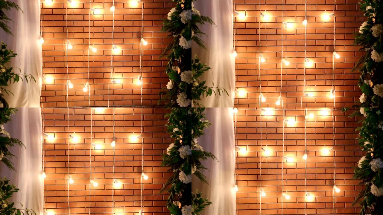 砖墙附近的灯泡花环。庆祝用灯装饰。