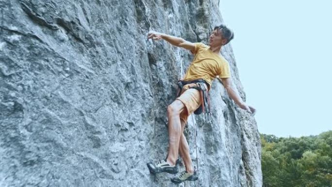 男子攀岩者在艰难的运动路线上挂在绳子上，休息和粉笔的手