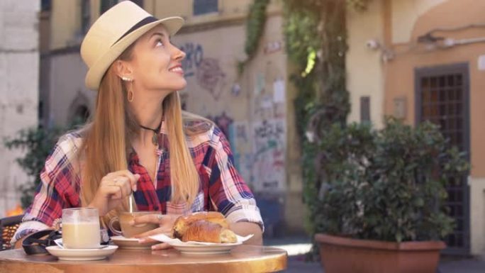 在意大利罗马的历史街区特拉斯特维里，一名金发碧眼的年轻女子正在典型的意大利酒吧里吃早餐。卡布奇诺，咖