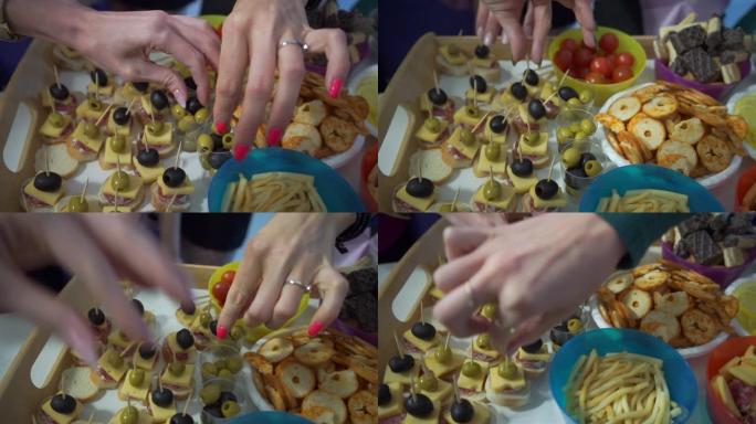 食物所在的桌子。女孩在派对自助餐上用手指拿食物。