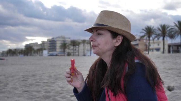女人坐在海边的海滩上吃西瓜