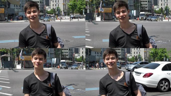千禧一代的韩国小伙子微笑着看着繁忙的林荫大道附近的镜头
