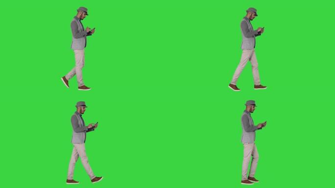 严肃的阿拉伯休闲男子在绿色屏幕上行走时使用智能手机，色度键
