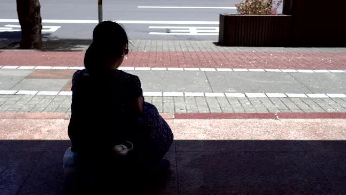 坐在公共汽车站的小女孩的剪影。