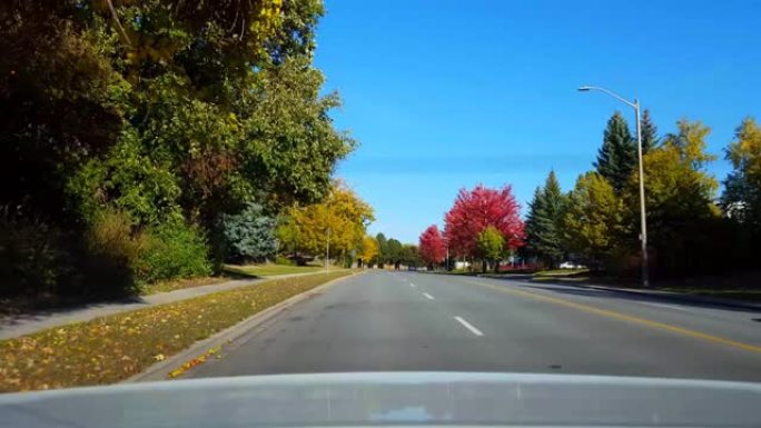 白天沿着道路行驶的汽车后部的后视图。汽车视点视点车辆后面明亮的白天天空。