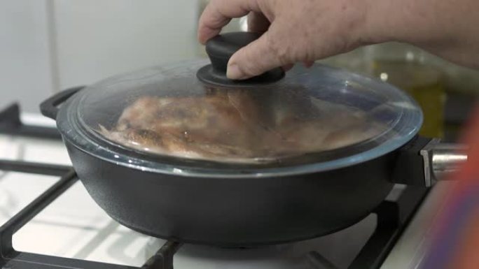 女人在铸铁煎锅里做煎鸡腿。