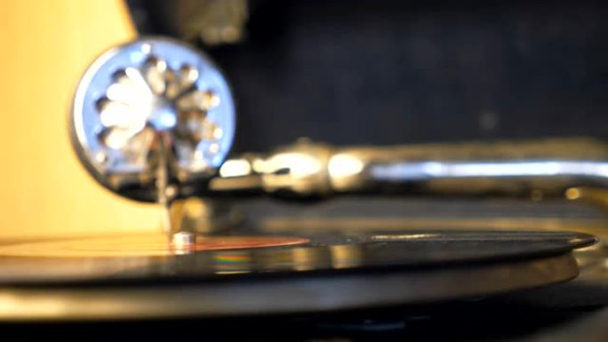 黑色乙烯基唱片在旧转盘上旋转的详细视图。带针的手写笔在背景上沿着复古板平稳滑动。演奏留声机的特写镜头