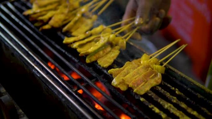 传统亚洲鸡肉烤肉串街头美食在泰国晚上的煤烧烤炉火上户外烹饪