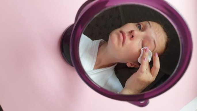 生活方式女人用化妆棉从脸上卸妆，镜子里倒影，面部护肤