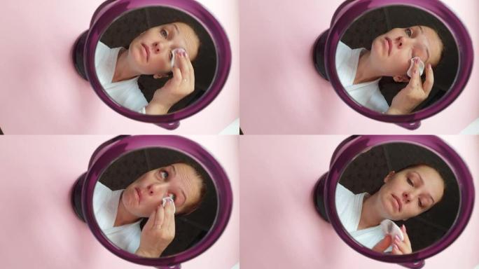 生活方式女人用化妆棉从脸上卸妆，镜子里倒影，面部护肤