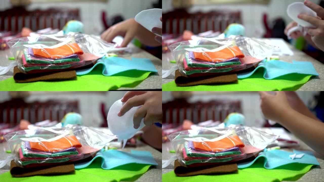 一个小孩在家用缝纫工具缝制衣服。手的特写。